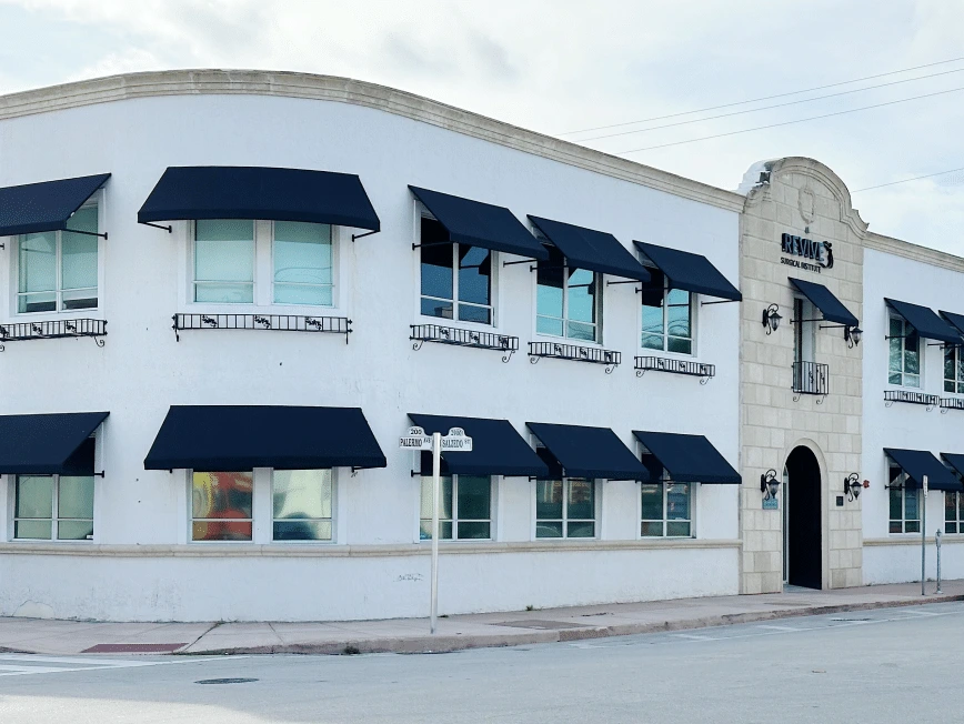 Revive Surgery clinic exterior with white and stone facade, navy awnings, Miami location