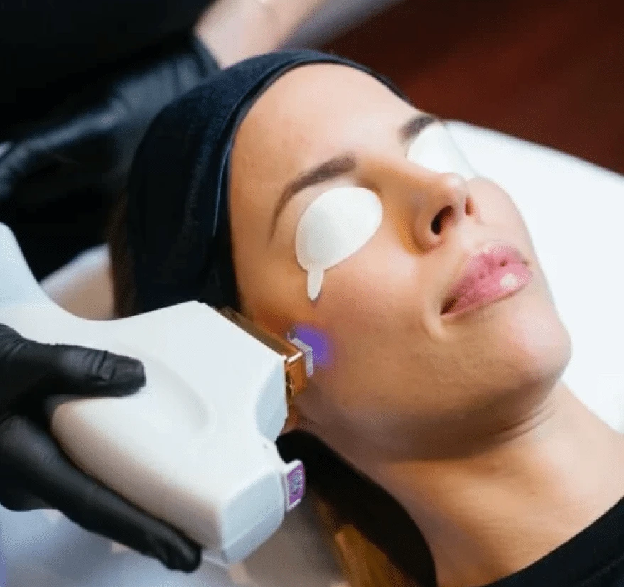 Clinician performing broadband light therapy on patient's face during skin treatment