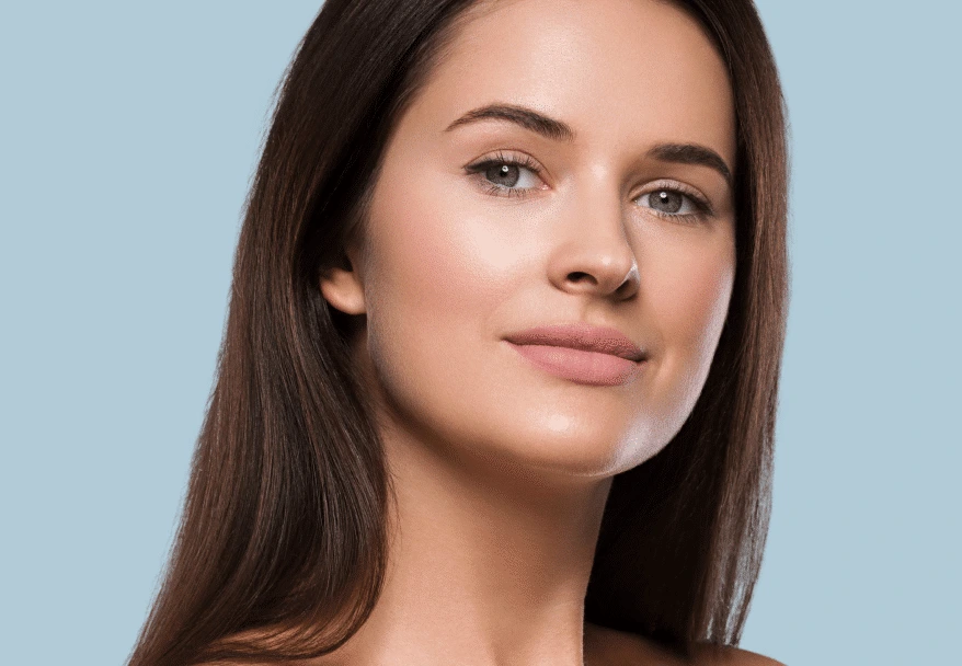 Woman with clear skin looking downward against blue background