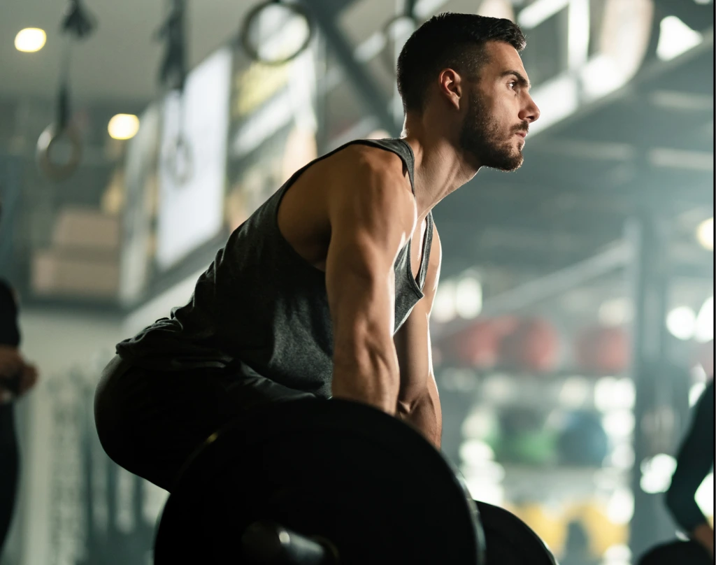 Man performing a squat exercise in a modern gym with large windows in background