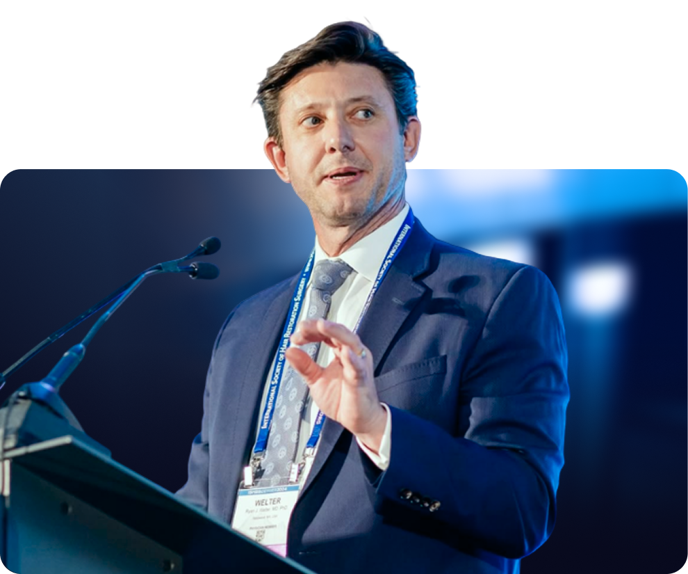 Man in dark suit speaking at podium wearing conference badge
