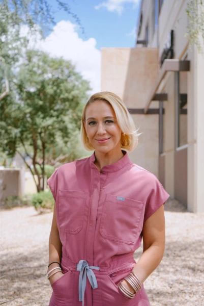 Staff member wearing pink vest standing outside modern building entrance