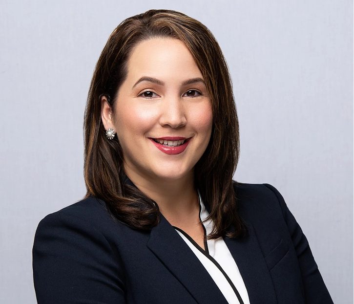 Ana Suarez smiling in professional headshot wearing navy blazer and white blouse