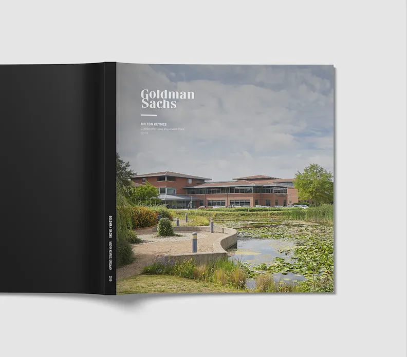 Goldman Sachs Hilton Keynes brochure with black cover open to image of modern brick building beside pond