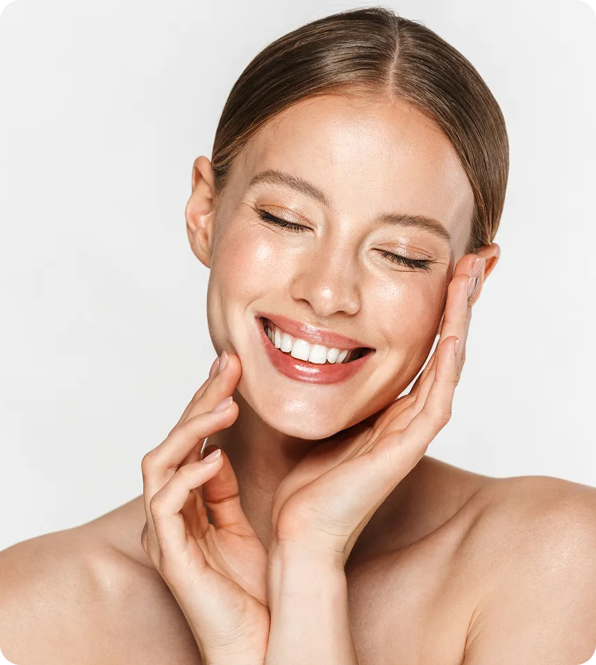 Woman with glowing skin touching her cheeks with both hands, smiling with eyes closed