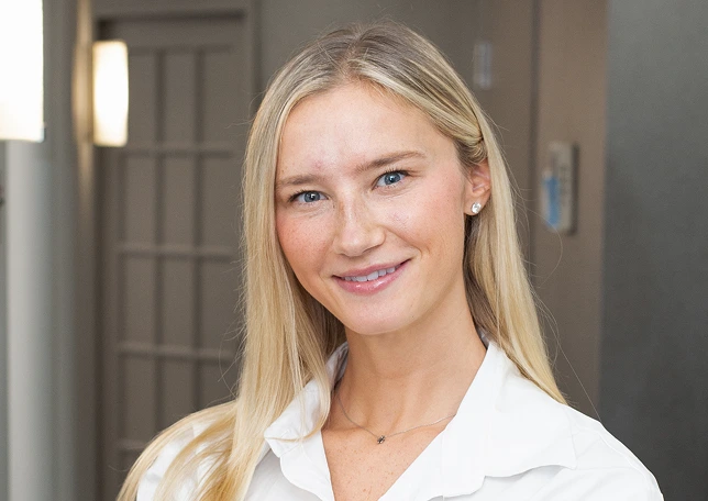 Female podiatry team member smiling in white coat in clinic interior