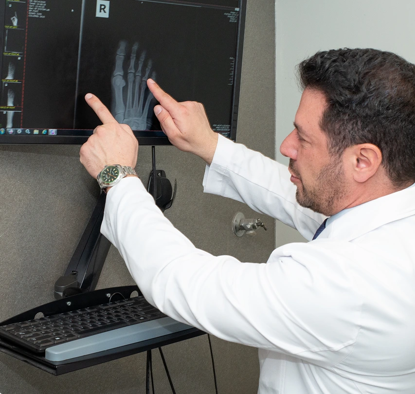 Podiatrist pointing to foot X-ray on monitor during patient consultation