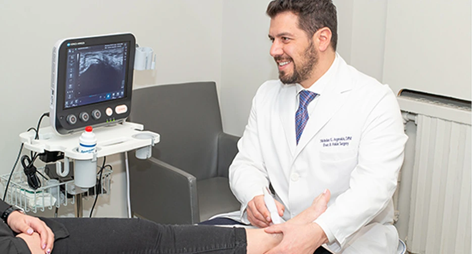 Podiatrist performing ultrasound examination on patient's foot using portable ultrasound machine