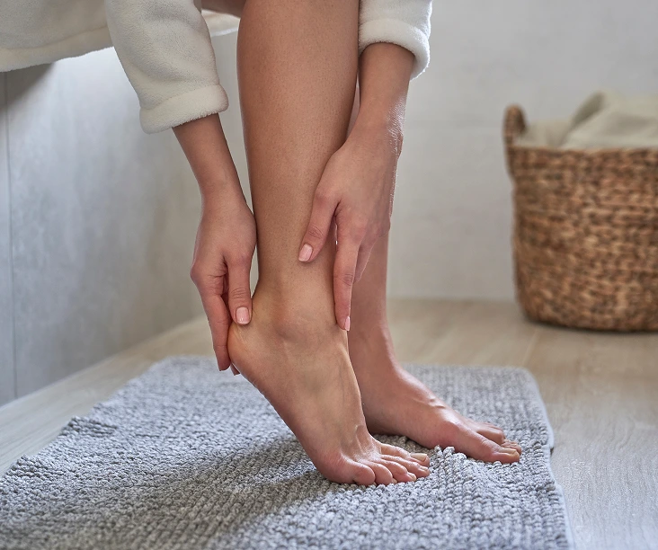 Podiatrist examining a patient's ankle and foot on a gray towel