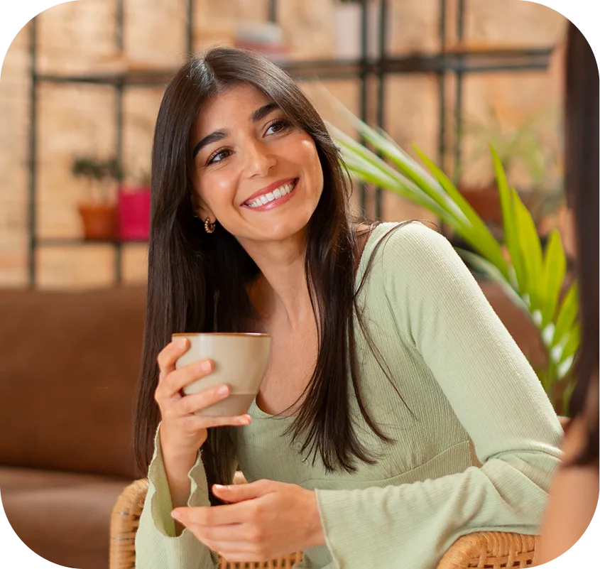 Smiling woman holding coffee cup in modern living room with potted plants