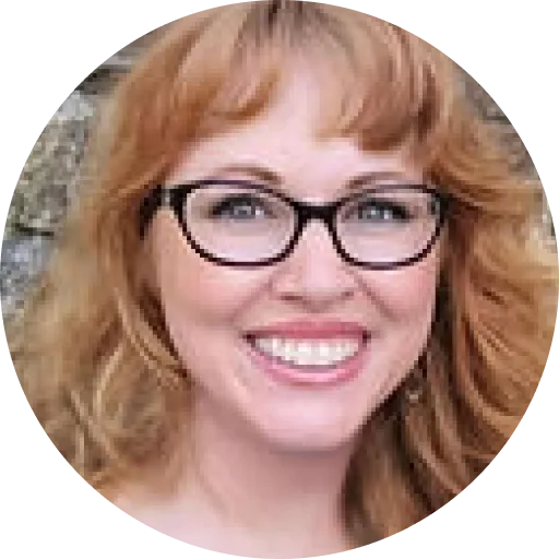 Ann Torres, woman with reddish-blonde wavy hair and glasses smiling at the camera