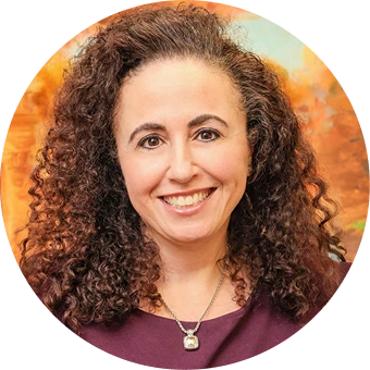 Circular portrait of a woman with curly brown hair wearing burgundy top against warm background