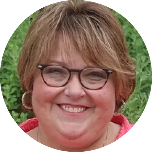 Lorri Frasier wearing glasses and red shirt, smiling at camera against green background