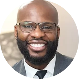 Michael, a man wearing glasses and a dark suit, smiling at the camera