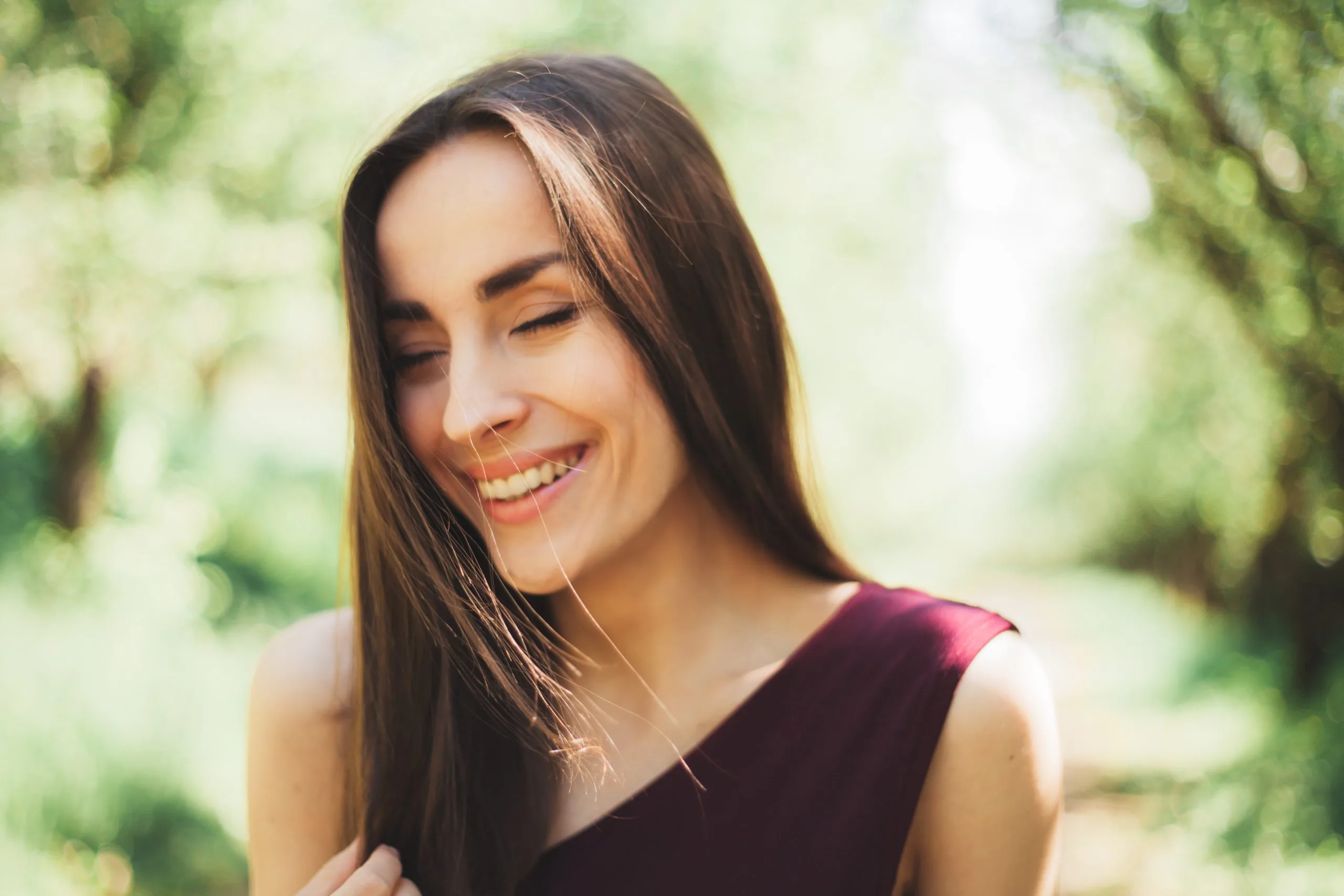 Woman with long dark hair smiling in natural outdoor lighting