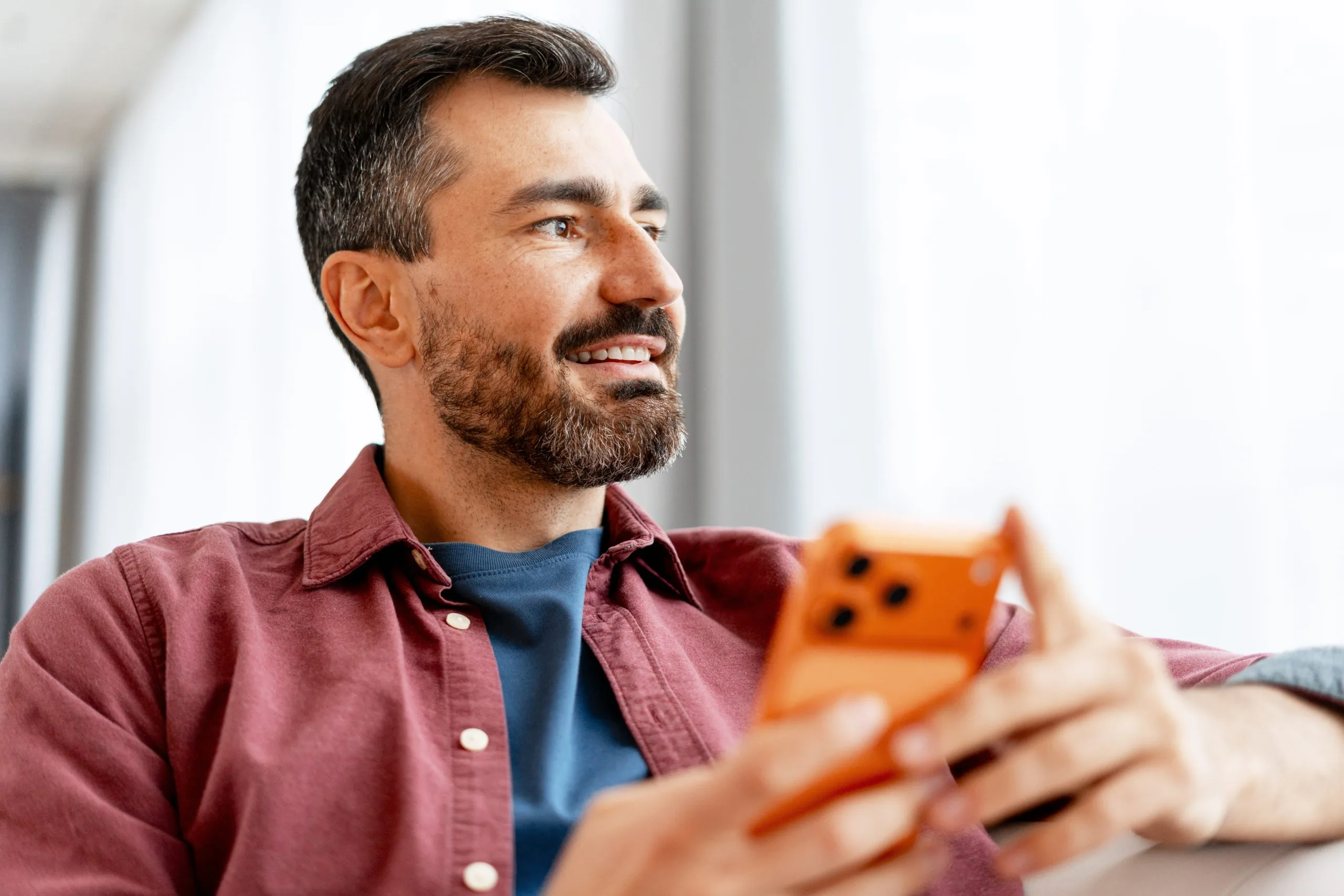 Man holding an orange stress relief toy while smiling