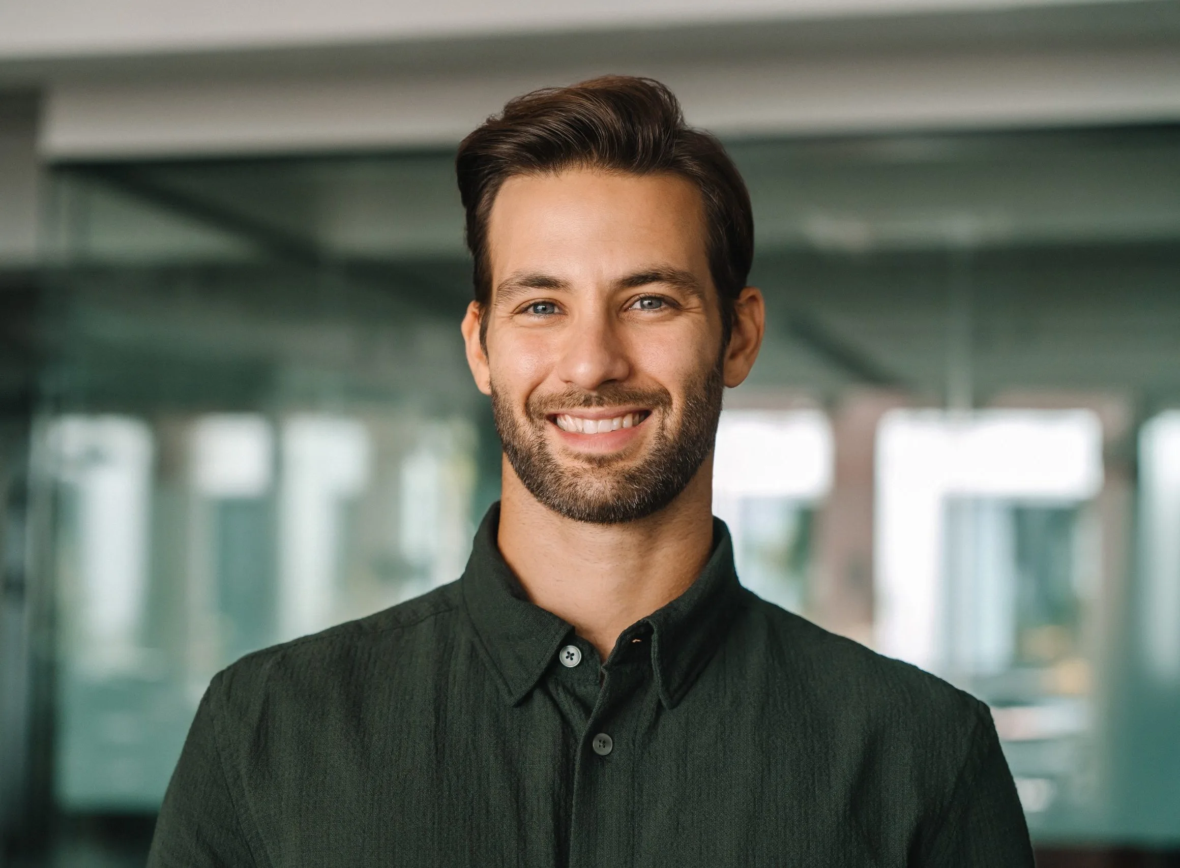 Professional headshot of a man smiling in a modern office setting