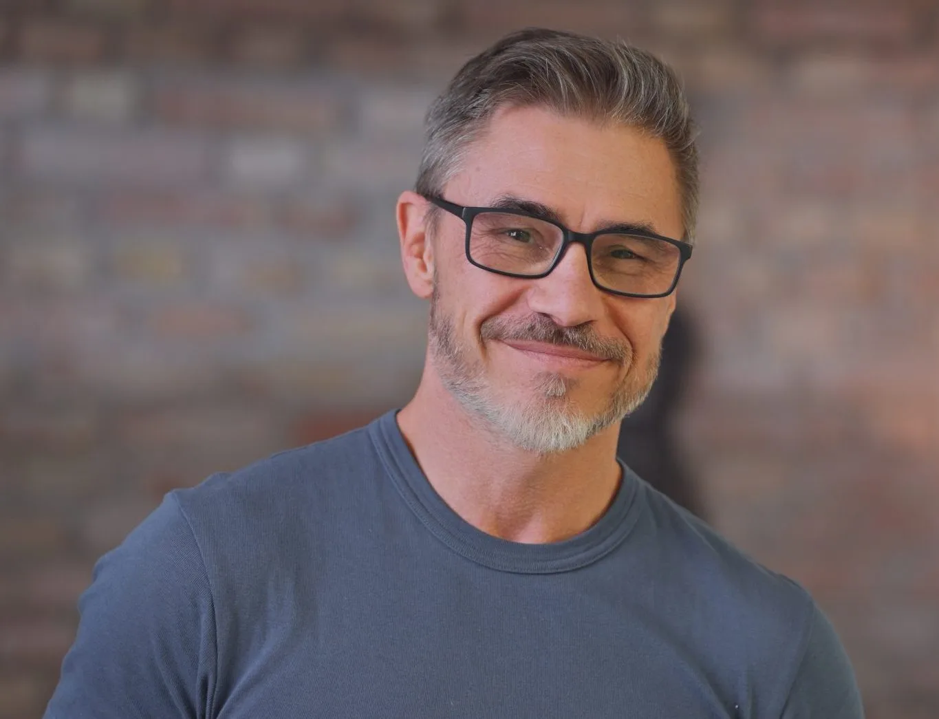Middle-aged man wearing glasses and blue shirt smiling at camera