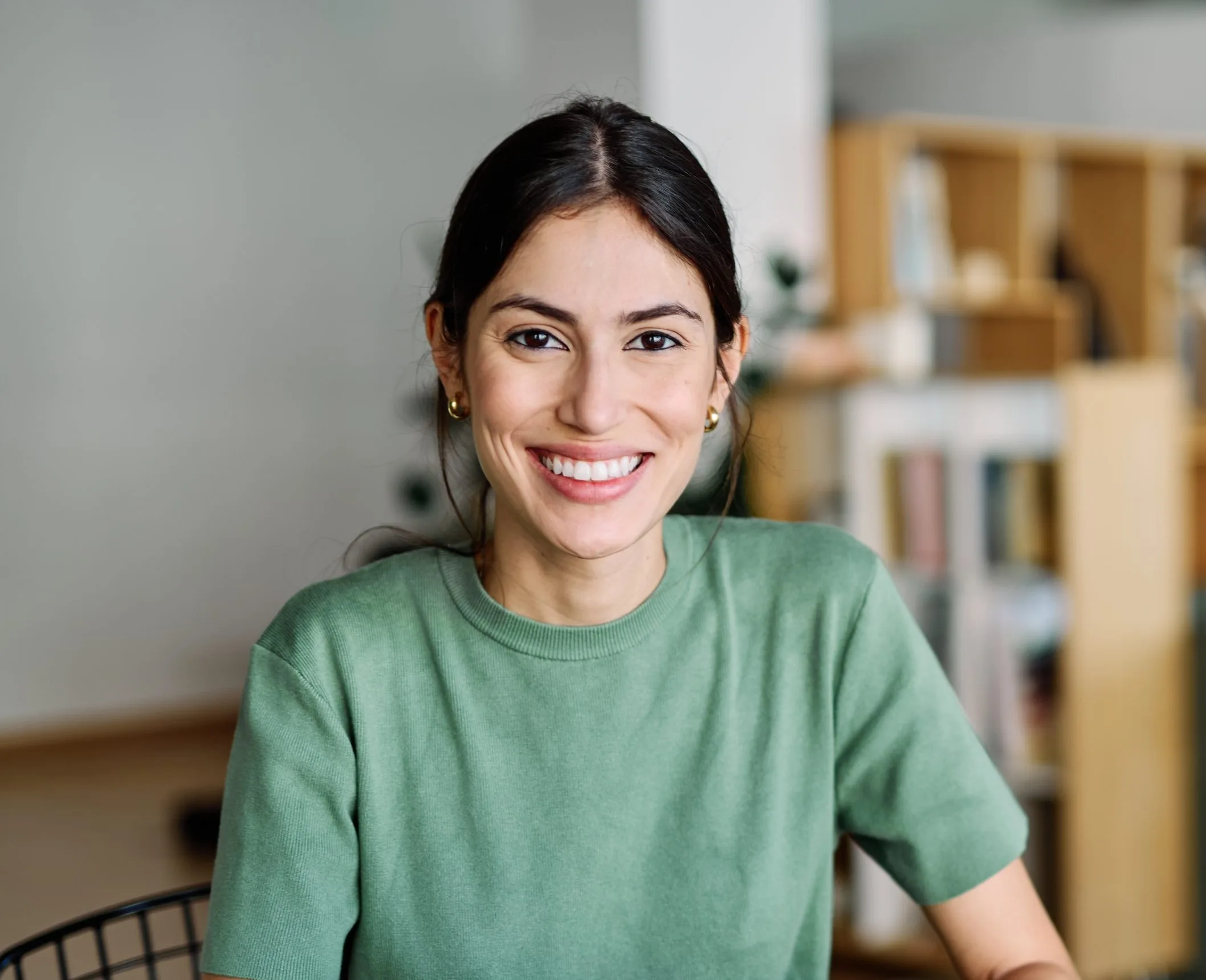 Woman smiling in a bright office setting with bookshelves in background