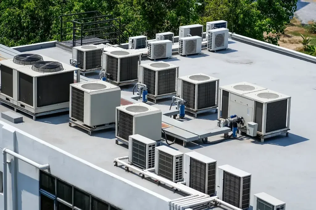 Commercial building roof with multiple HVAC units and air conditioning systems installed on white surface
