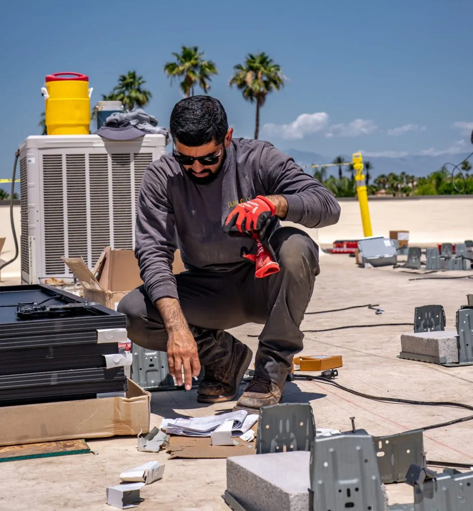 Technician assembling electrical components on rooftop near AC condenser unit