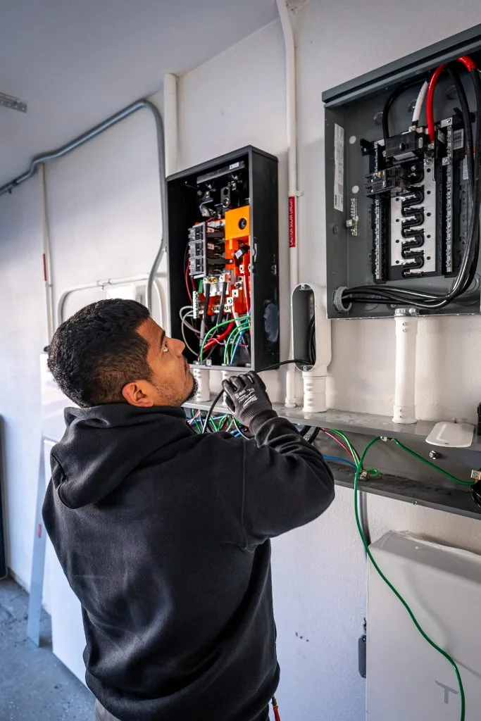 Technician servicing electrical panels and wiring for commercial refrigeration system