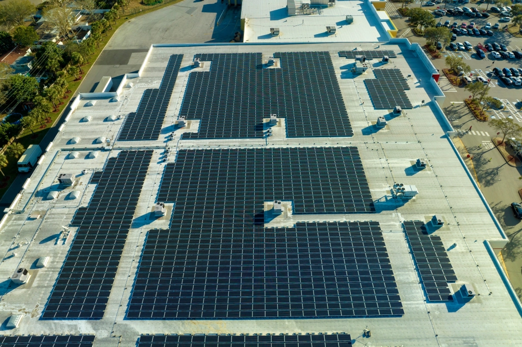Aerial view of commercial rooftop with multiple solar panel arrays installed on white surface