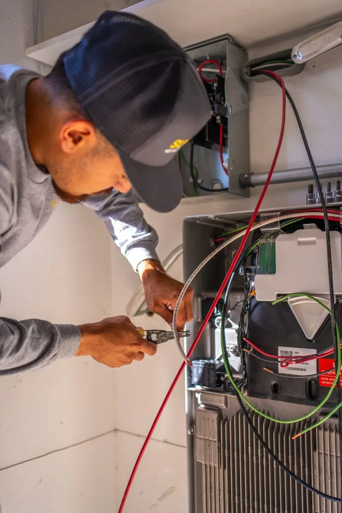 Technician testing HVAC system connections with multimeter during inspection