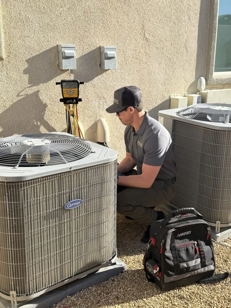 Technician servicing Carrier AC units on building rooftop with measurement equipment