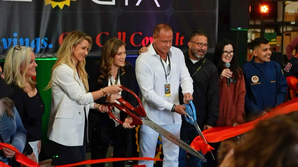 Group of six people cutting red ribbon at a business opening ceremony
