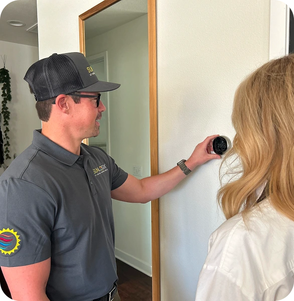 Sunlogix technician showing woman smart thermostat installation on interior wall