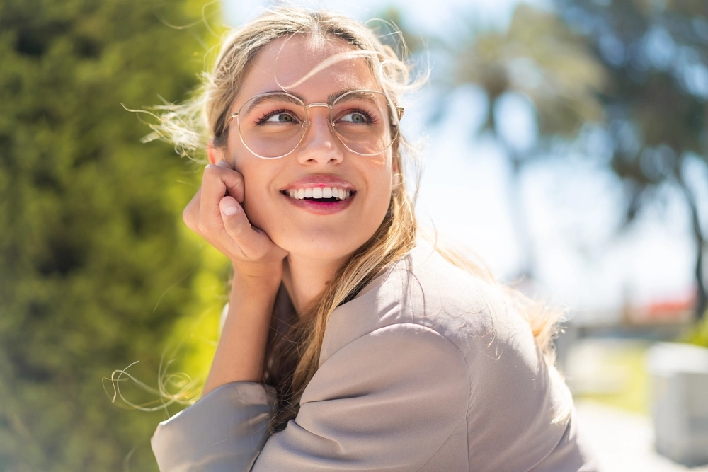 Woman in glasses smiling outdoors in natural sunlight