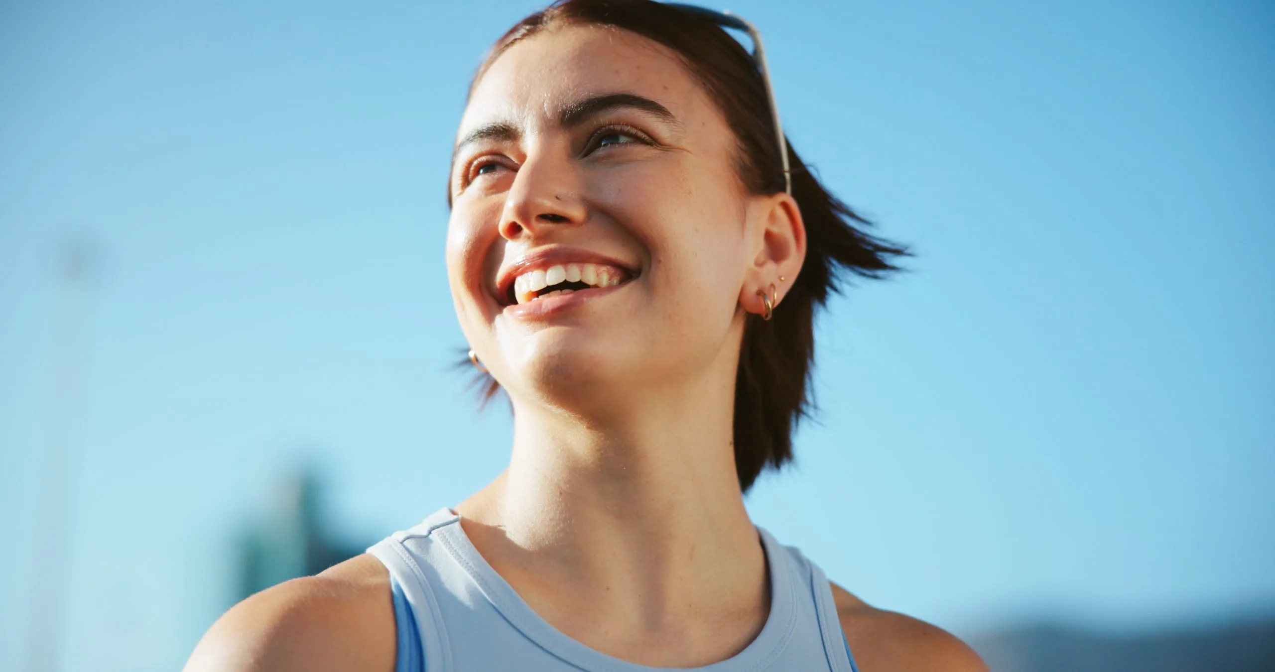 Woman smiling outdoors against a clear blue sky