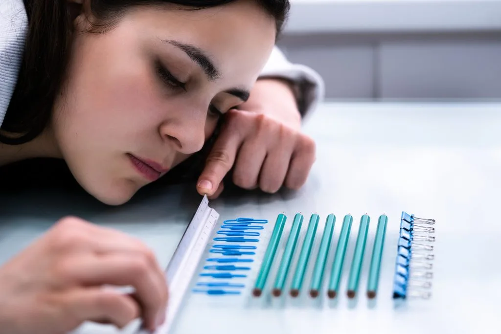 Woman examining paint color swatches on table while holding clipboard
