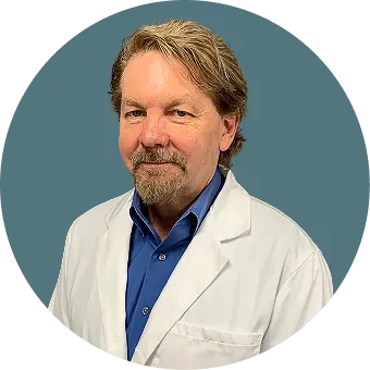 Man with goatee wearing white medical coat and blue shirt, headshot