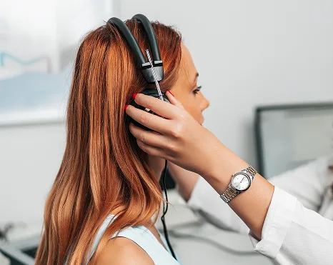 Clinician performing otoscopic examination on patient with long reddish-brown hair