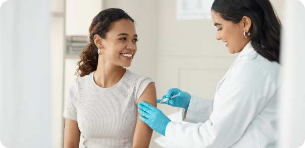 Healthcare provider in white coat administering injection to patient's arm