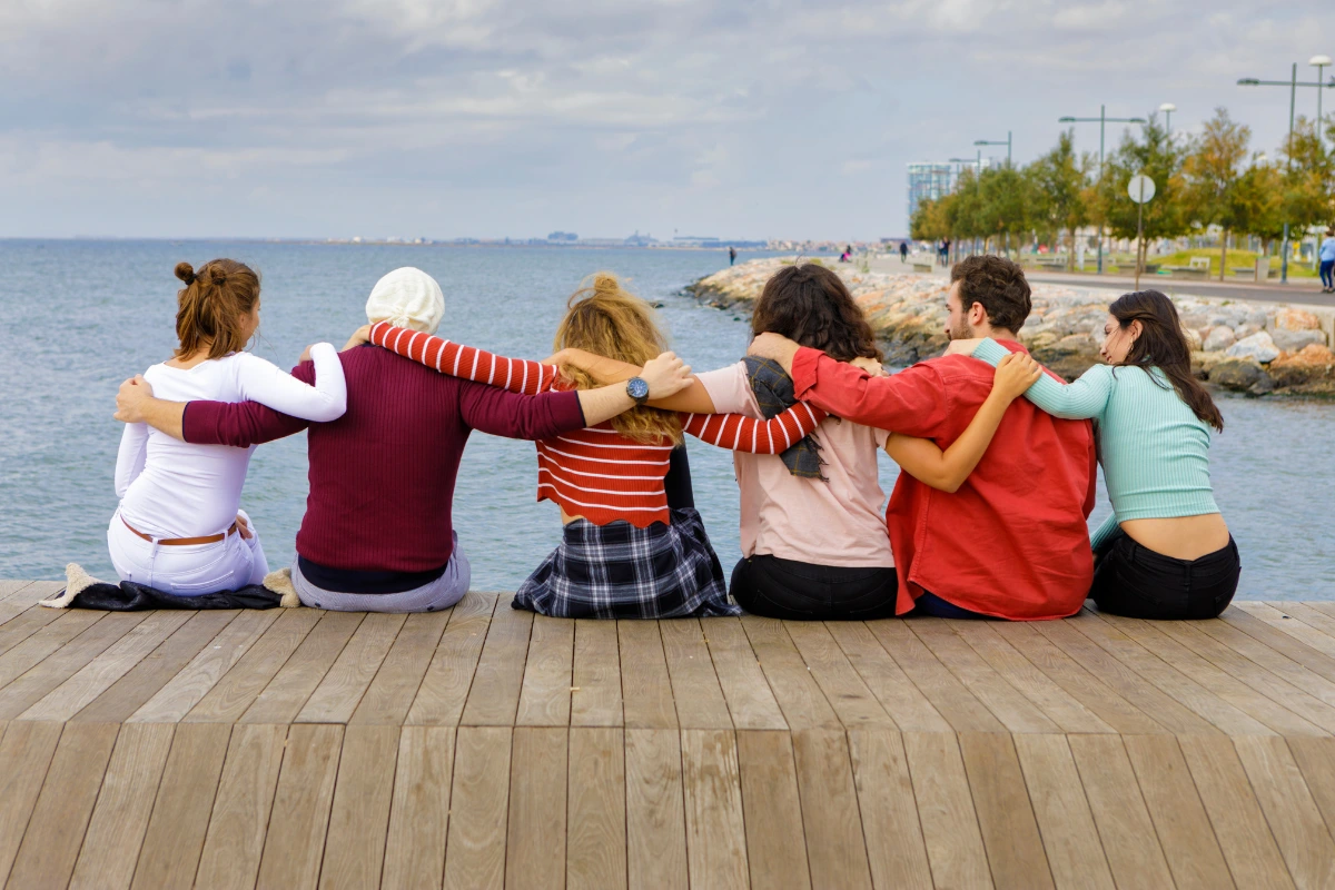A group of friends with ADHD linking arms on a dock at the beach.