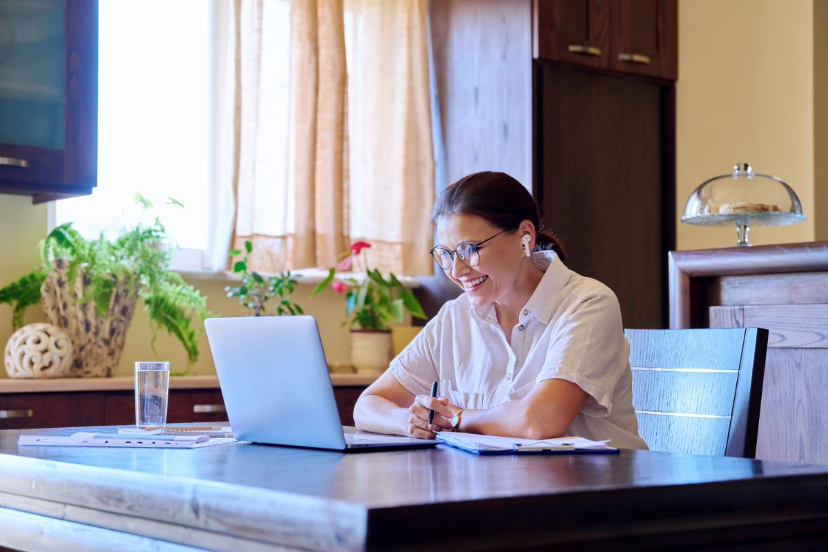 Doctor in white coat consulting with patient via laptop during online ADHD therapy session in bright office