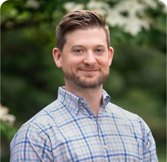 Matt Hanley, Psychologist at The Center for ADHD, smiling outdoors in a blue plaid shirt