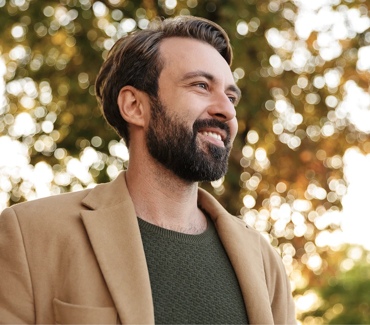 Man smiling outdoors with blurred golden foliage background