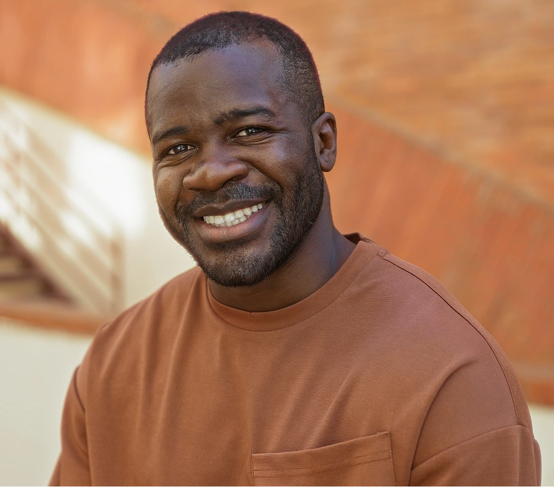 Man smiling at camera against warm-toned brick background