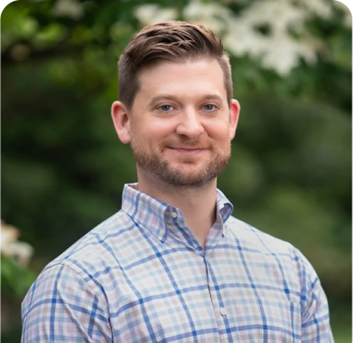 Mike Molloy, LCSW, therapist at The Center for ADHD, smiling outdoors in a blue plaid shirt
