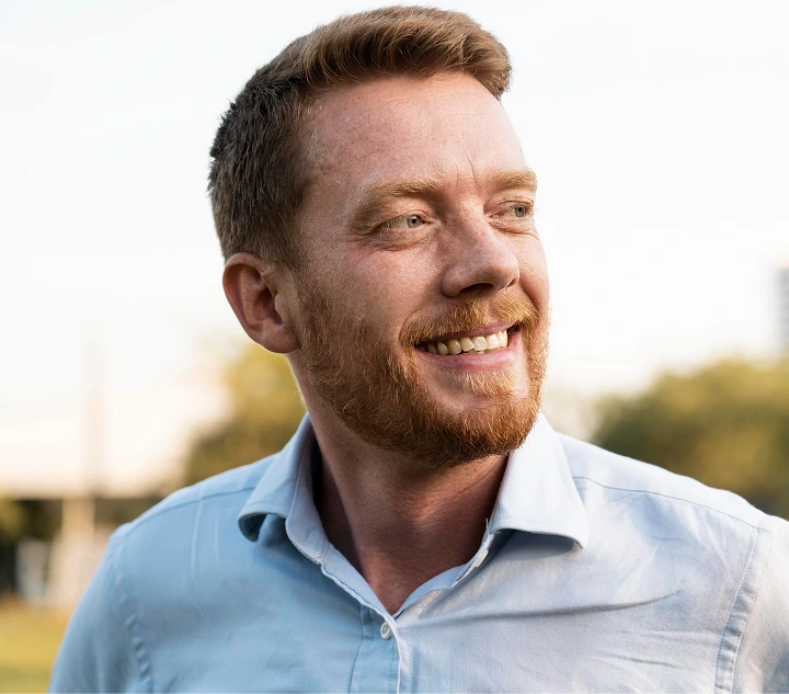Adult man smiling outdoors in casual blue shirt