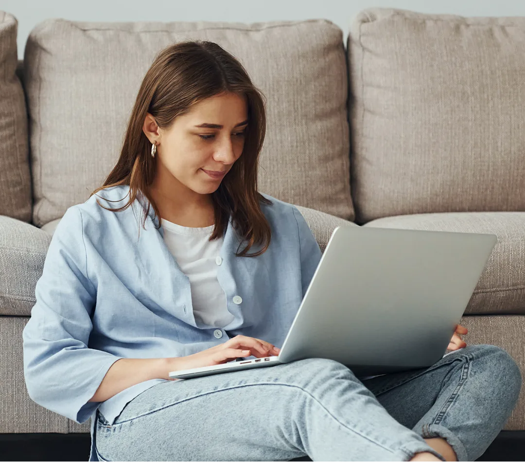 Woman using a laptop while seated on a couch for a virtual ADHD testing session