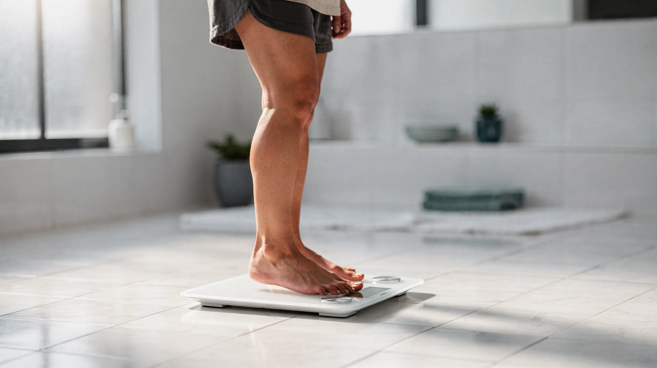 Woman stepping onto a digital bathroom scale to check her weight