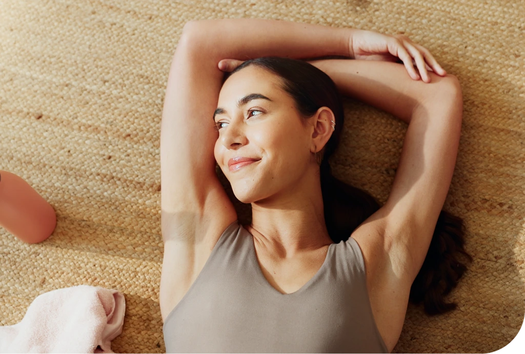 Woman lying on textured background with arms raised, smiling peacefully