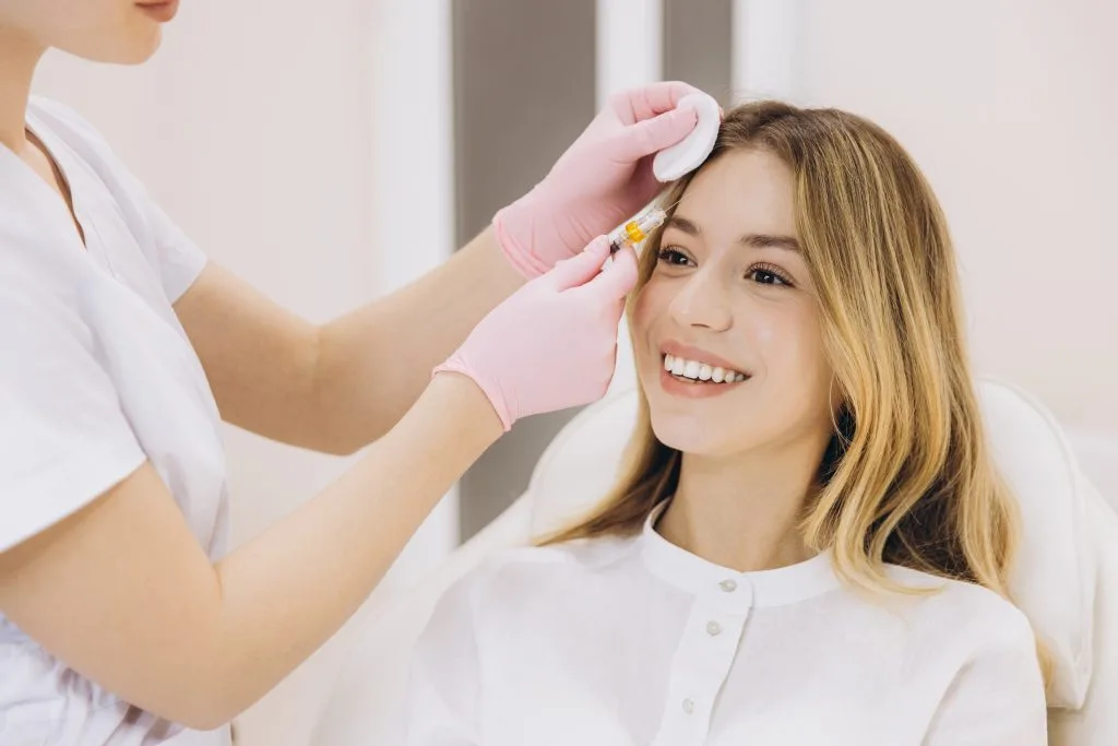 Aesthetic practitioner applying injectable treatment to patient's forehead
