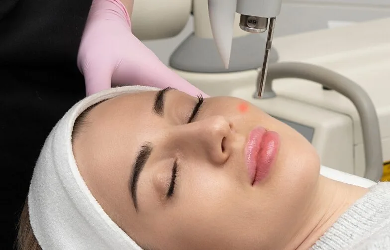 Aesthetician in pink gloves applying facial treatment to relaxed patient in clinical spa setting