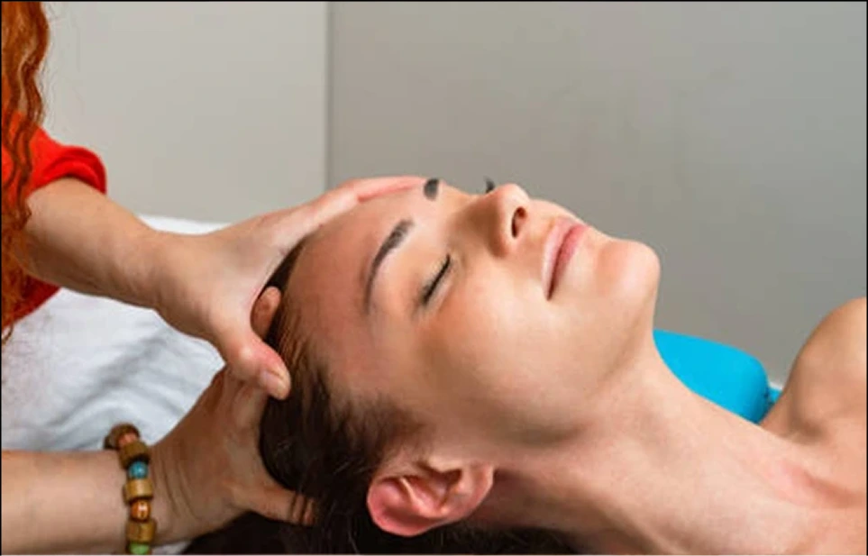 Therapist massaging client's head and temples during facial treatment